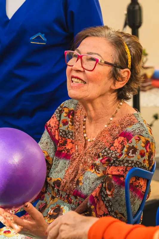 Moradora sorrindo durante atividade com bola na unidade Calafate/Prado