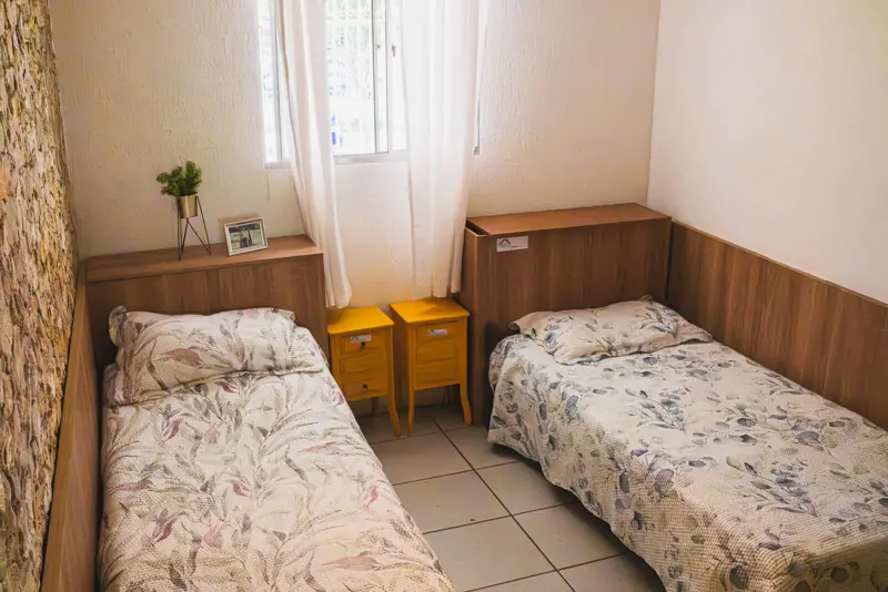 Quarto com duas camas e criados-mudos na unidade Calafate/Prado