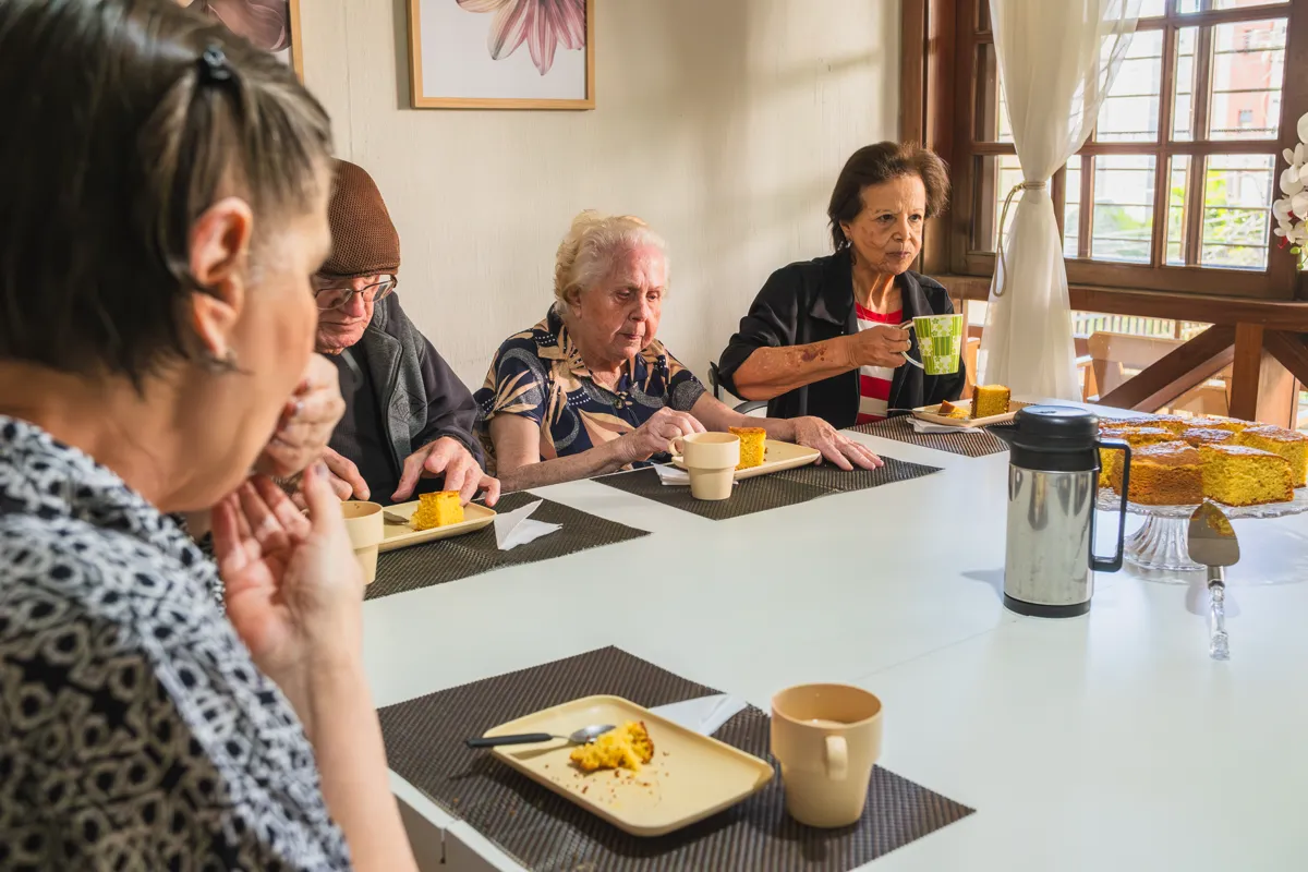 Refeição em grupo à mesa, com café e bolo