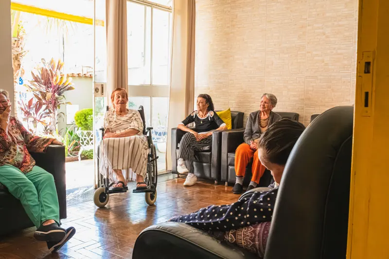 Sala de convivência com moradores e poltronas na unidade Calafate/Prado