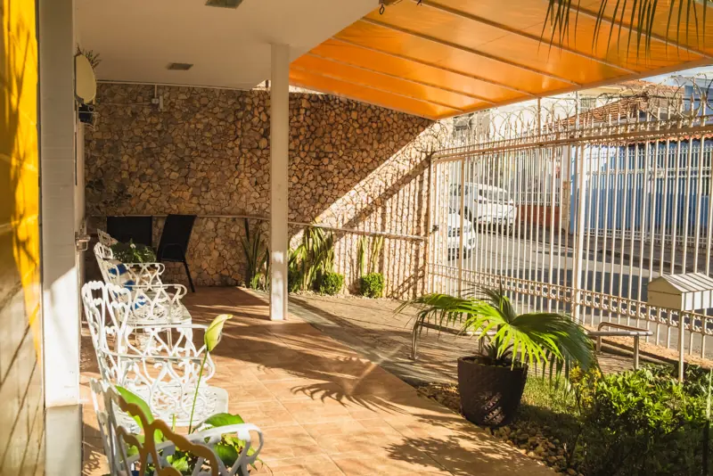 Varanda com bancos de ferro branco e plantas na unidade Calafate/Prado