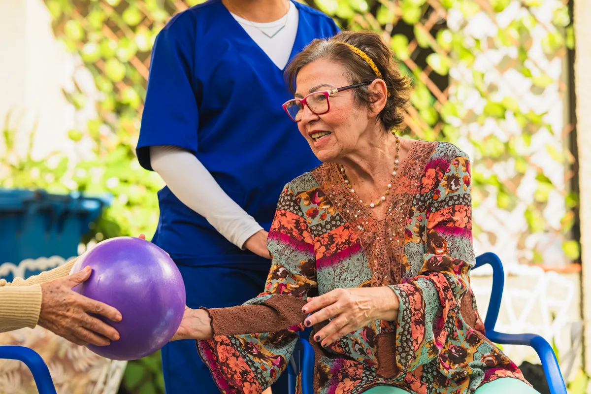 Moradora em exercício com bola junto da cuidadora