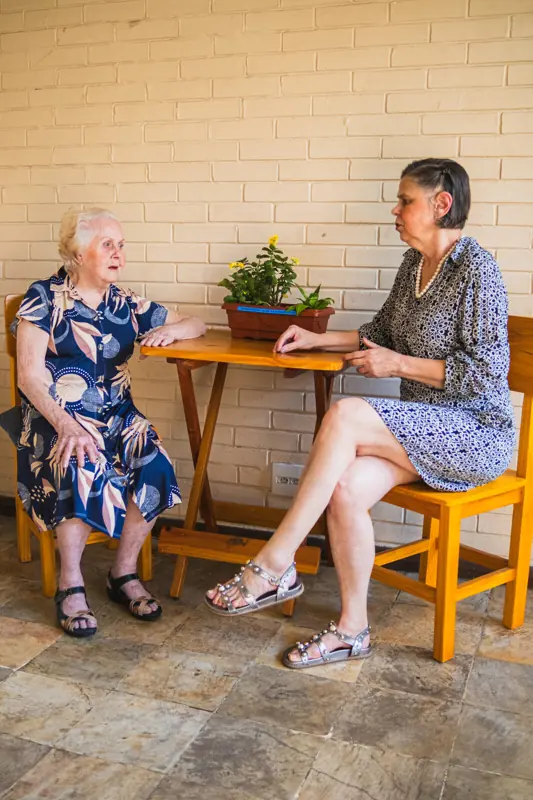 Moradoras conversando à mesa na varanda da unidade Gutierrez