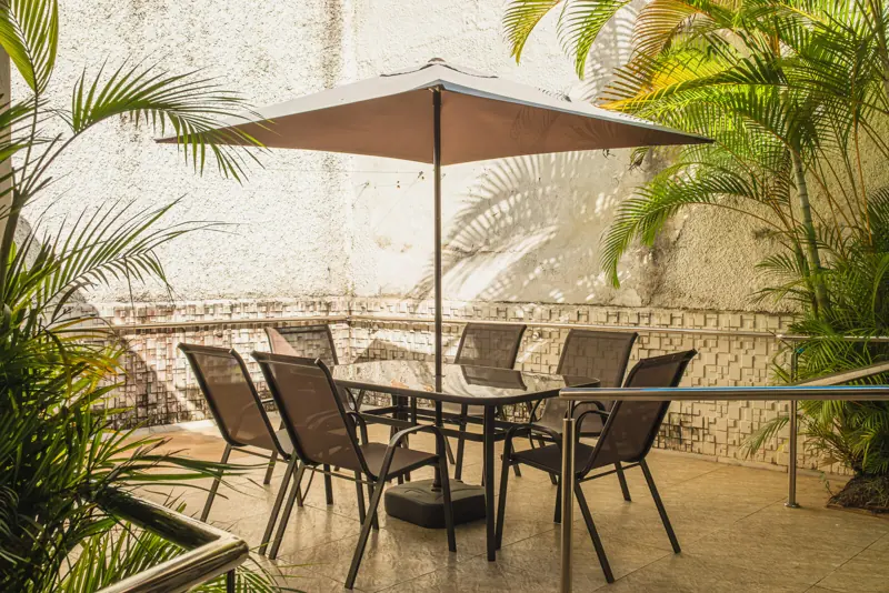 Pátio com guarda-sol, mesa e plantas na unidade Gutierrez