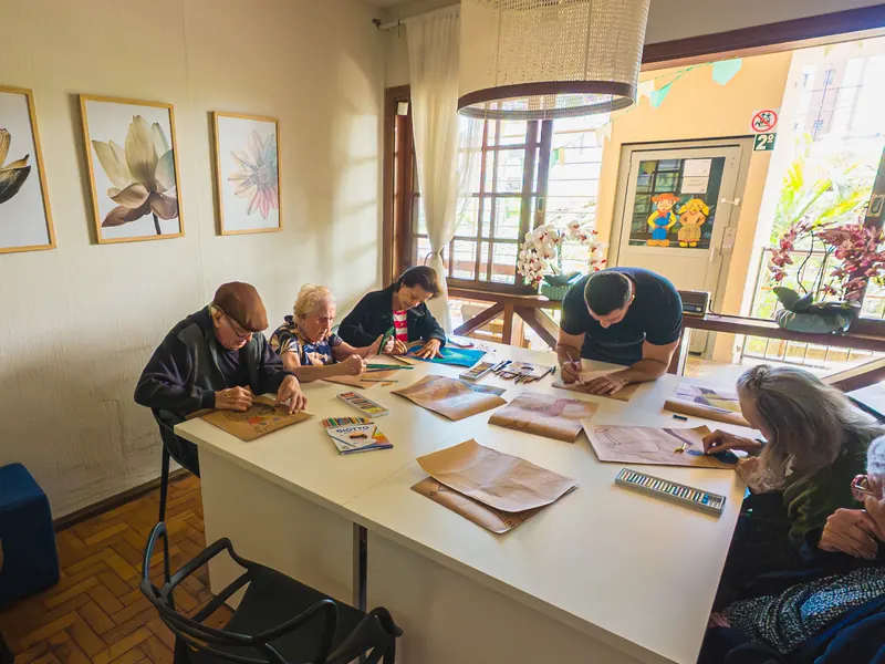 Sala do segundo andar da unidade Gutierrez, com moradores em atividade à mesa