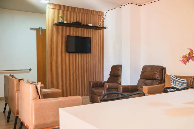 Sala de estar com TV e poltronas reclináveis na unidade Gutierrez